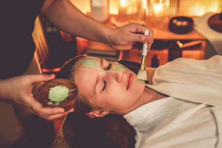 Serene ambiance of spa salon, woman customer indulges in rejuvenating with luxurious face cream massage with warm lighting candle. Facial skin treatment and beauty care concept. Quiescentの写真素材