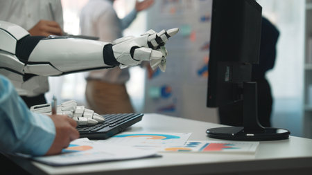 A robotic hand pointing at a computer screen, showcasing business charts and data analysis in a...