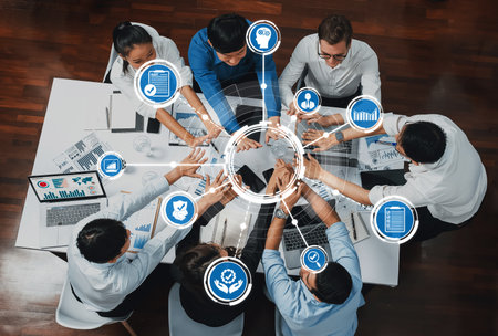 A top-down view of a business meeting with professionals collaborating to analyze data and make decisions, surrounded by technology and charts in a modern office.の写真素材