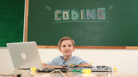 Smart student working on electronic board while looking at camera with blackboard. Child fixing main board while prepare for programing system by using coding engineering and AI. Pedagogy.の写真素材
