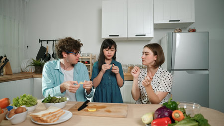 Happy father move to music while cooking food and prepare lunch at modern kitchen. Active dad dancing to song while making healthy food or salad surrounded with vegetable and kitchenware. Pedagogy.の写真素材