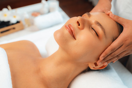 Caucasian woman enjoying relaxing anti-stress head massage and pampering facial beauty skin recreation leisure in dayspa modern light ambient at luxury resort or hotel spa salon. Quiescentの写真素材