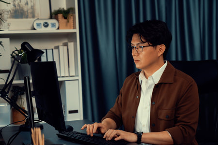 Smart businessman in casual day focusing computer to create business plan report over late night time at office, working on searching tools market planning with new startup company project. Infobahn.の写真素材