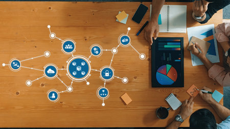 Engaging overhead view of a diverse group collaborating in a modern workspace, utilizing data visualization tools and charts to enhance business strategies and decision-making. Amityの写真素材