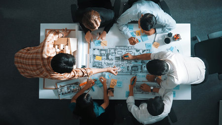 Top aerial view of project manager or civil engineer writing at blueprint and planning building...