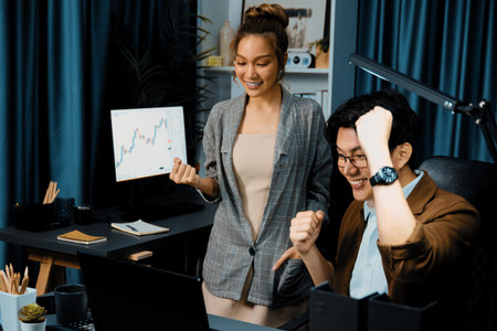 Successful wealthy of smiling business trader with partner in casual suit earning high profit raising fist up in exchange stock market investment in technology at modern office at night. Infobahn.の写真素材