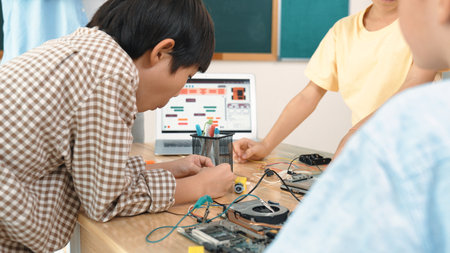 Group of diverse student working together on main board with laptop screen display engineering...