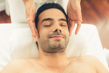 Caucasian man enjoying relaxing anti-stress head massage and pampering facial beauty skin recreation leisure in dayspa modern light ambient at luxury resort or hotel spa salon. Quiescentの写真素材
