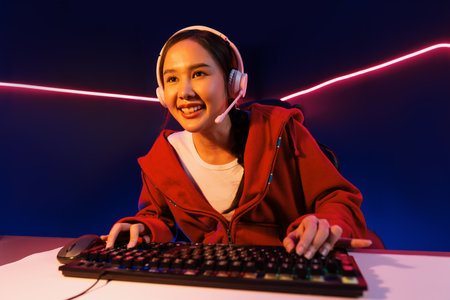 Host channel of smiling beautiful Asian girl streamer playing online game wearing headphone talking...
