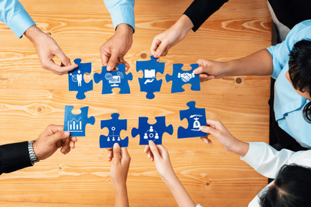 A diverse team actively collaborates, holding colorful puzzle pieces featuring business icons. This...
