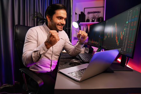Smart trader businessman concentrating on dynamic stock exchange investment on pc and laptop showing on screen with high profit in searching market at neon light office in dark room night. Surmise.の写真素材