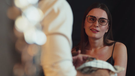 Portrait of beautiful woman lively conversation with bartender at back side while cleaning equipment...