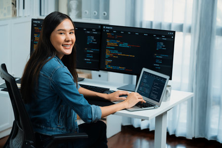 Young Asian in IT developer looking at camera to present with online information on pc with coding...