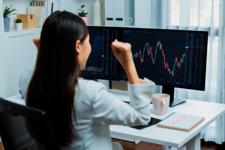 Successful young Asian businesswoman earning highest profit with fist up in exchange stock market on...