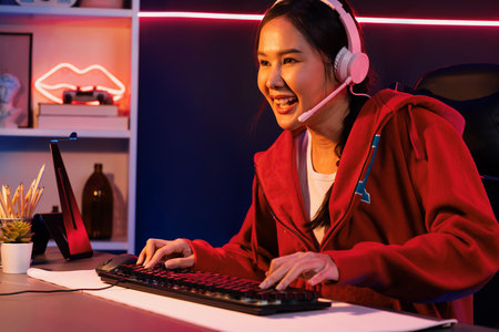 Host channel of smiling beautiful Asian girl streamer playing online game wearing headphone talking...