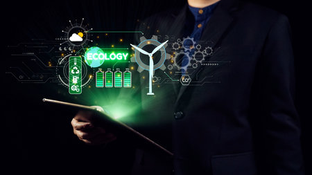 A business professional holds a tablet displaying digital graphics related to ecology and renewable...