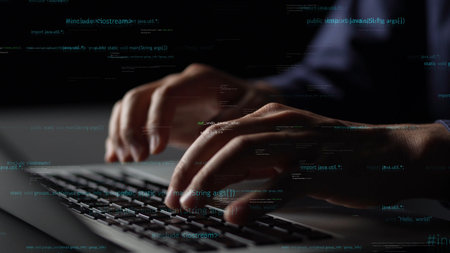 A close-up of hands of a programmer typing on a laptop, with digital code hovering in the air,...