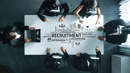 A high-angle view of a professional business meeting focused on recruitment strategy, showcasing...