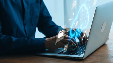 Hands typing on laptop with digital interface and icons representing technology, data,...