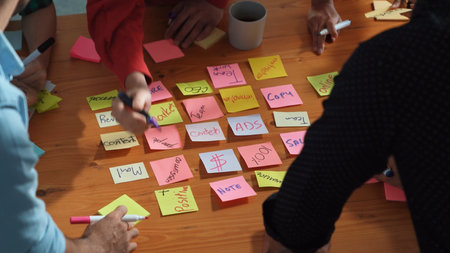 Top down aerial view of creative people hands writing idea on sticky notes at meeting table. Close up of diverse business people hand in casual cloth placed planning strategy on table. Convocation.の写真素材