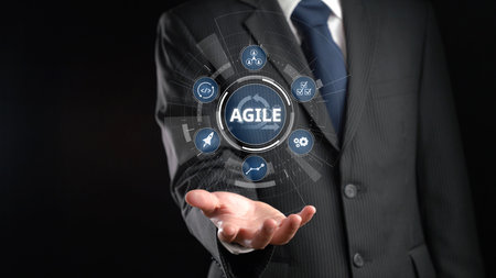 A professional businessman showcases an agile concept with floating icons above his hand in a dark...