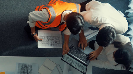 Top down view of project manager and civil engineer hold laptop while explain idea to architect....