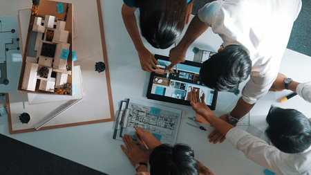 Top down view of architect engineer team discussing and pointing at tablet display construction at...
