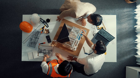 Top view of skilled architect designer team using pencil measuring house model. Group of civil engineer planning and designing blueprint while pointing at building at table with laptop. Alimentation.の写真素材
