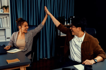 Successful smiling business partners earning high revenue in sales taking high five in creative...