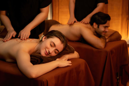 Couple customer having exfoliation treatment in luxury spa salon with warmth candle light ambient. Salt scrub beauty treatment in Health spa body scrub. Quiescentの写真素材