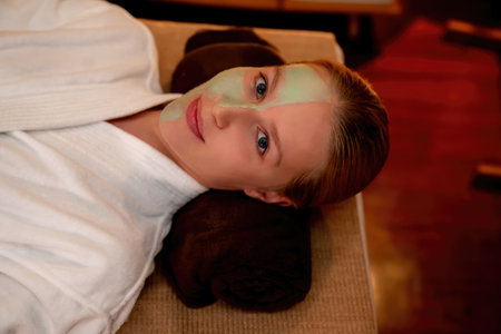 Serene ambiance of spa salon, woman customer smiling and rejuvenating with luxurious face cream massage with warm lighting candle. Facial skin treatment and beauty care concept. Quiescentの写真素材