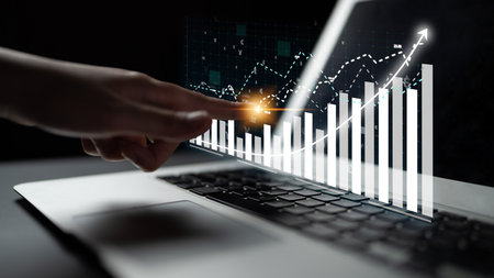 A person interacts with a touchscreen graph displayed on a laptop, illustrating business growth and progress through digital technology in a modern workspace. Imputeの写真素材