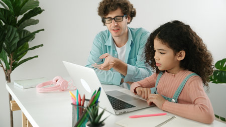 Caucasian father help student doing homework about engineering code while happy school girl. Dad take care cute child while teaching about generative AI at table with laptop and headphone. Pedagogy.の写真素材