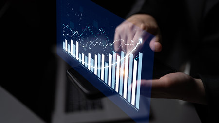 A professional setting showing a hand interacting with digital graphs and charts on a smartphone,...