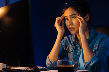Stressful young asian creative looking on pc to search project creator social media online with...