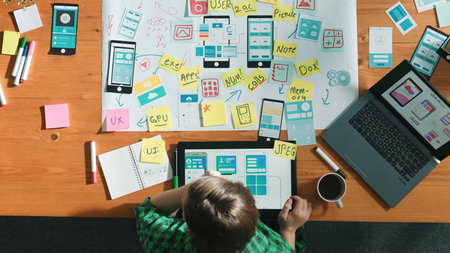 Top view of smart developer working on tablet and writing Ux Ui design for mobile phone interface at...