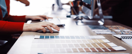 A modern workspace featuring hands engaged in a collaborative design process, showcasing color...