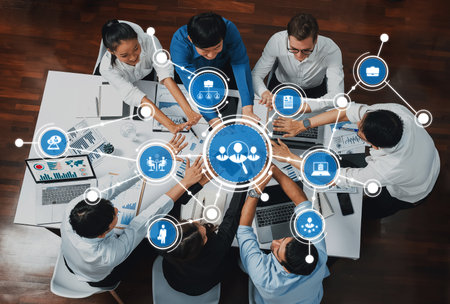 A diverse group of professionals collaborates around a table, utilizing technology and data visualization to enhance teamwork and productivity in a modern office setting.の写真素材