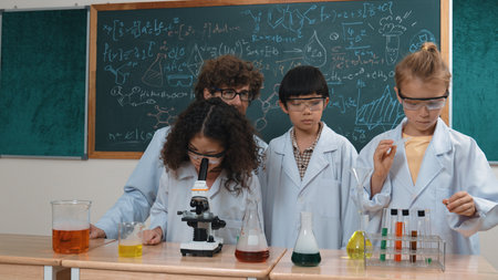 Skilled diverse children looking under microscope while caucasian student prepare chemical solution....