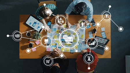 Aerial view of professionals collaborating over a table with various tools and ERP solutions. Emphasis on creativity and strategic planning in a business environment.の写真素材