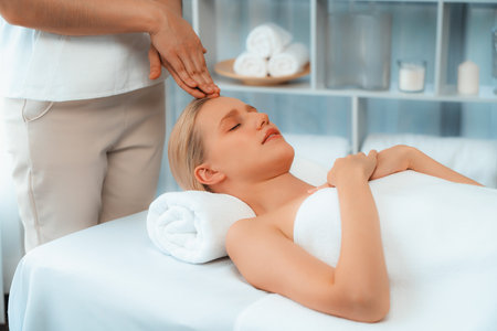 Caucasian woman enjoying relaxing anti-stress head massage and pampering facial beauty skin recreation leisure in dayspa modern light ambient at luxury resort or hotel spa salon. Quiescentの写真素材