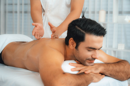 Caucasian man customer enjoying relaxing anti-stress spa massage and pampering with beauty skin recreation leisure in day light ambient salon spa at luxury resort or hotel. Quiescentの写真素材