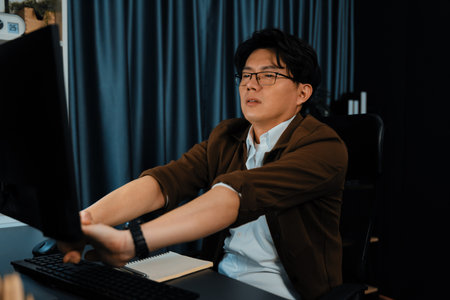 Creative manager working on desk with stretching arm up and down manner with body health ache of...
