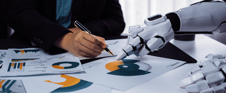 A human hand writing notes alongside a robotic hand, reflecting the integration of technology into...