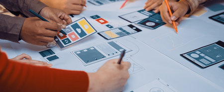 A dynamic team collaborates on app design, using colorful sketches and notes on a table. The scene...