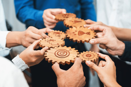 A diverse group of hands hold wooden gears, symbolizing teamwork and collaboration in a business...