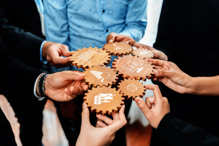A group of professionals collaboratively holding wooden gears with symbols representing various...