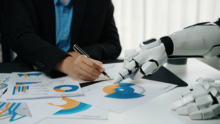 A futuristic setting where a robot collaborates with a human, showcasing charts and graphs. This image represents the blending of technology with human creativity in the workplace.の写真素材