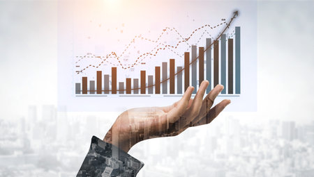 A conceptual image illustrating business growth with a hand holding charts and graphs, representing financial progress and success over a city backdrop. Imputeの写真素材