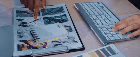A modern workspace scene featuring hands pointing at a colorful mood board alongside a keyboard and a notebook, reflecting the design and creative process in action.の写真素材